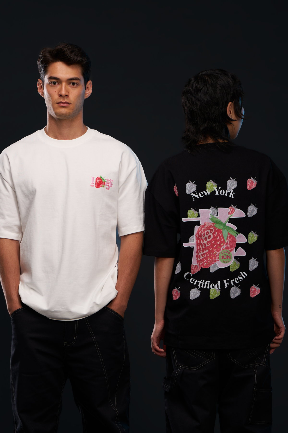 ICHIGO. TEE in white and black — worn, two models side by side, white chest logo and black back strawberry graphic