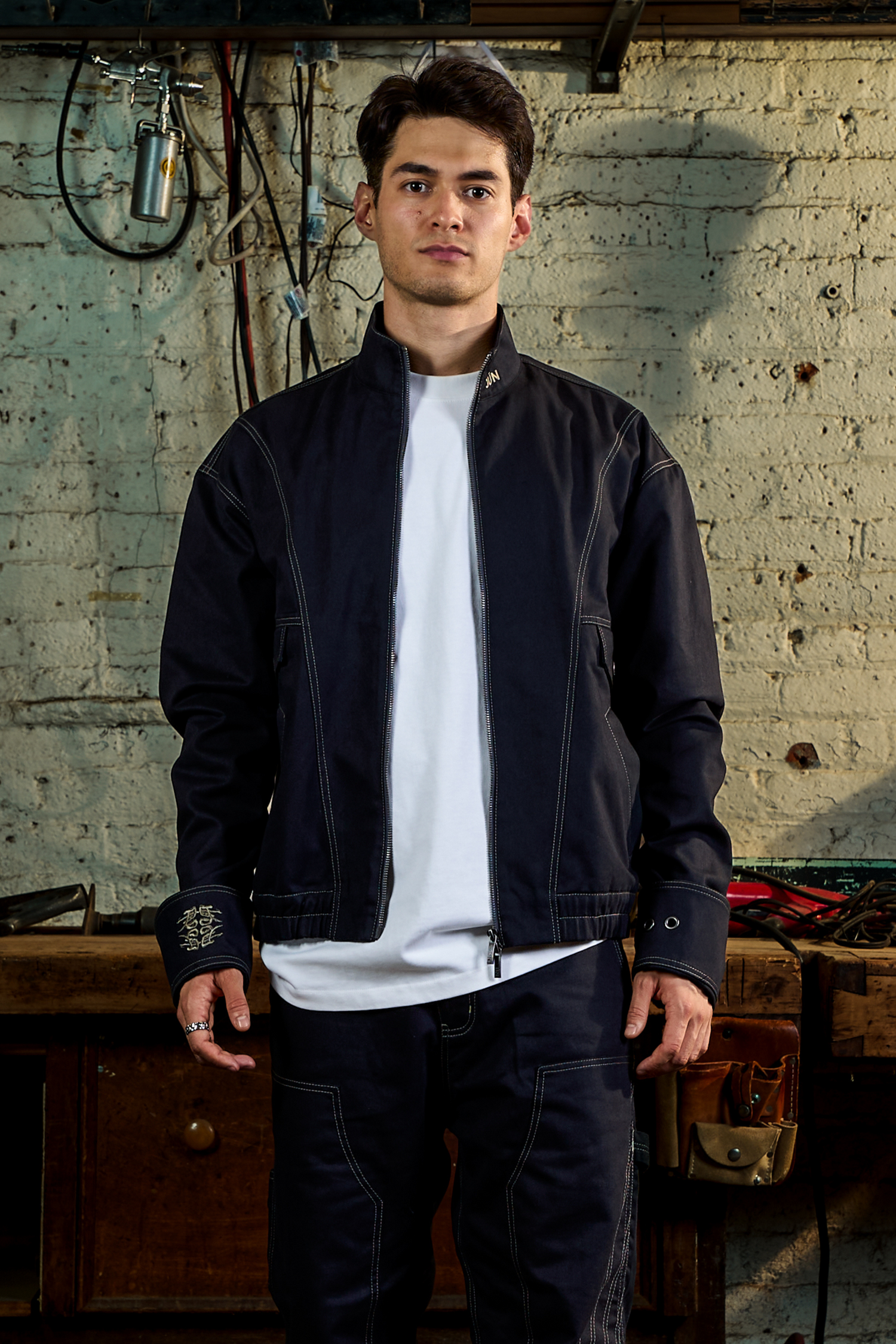 ONYX. JKT in navy — front, worn open, styled with a white tee, garage setting