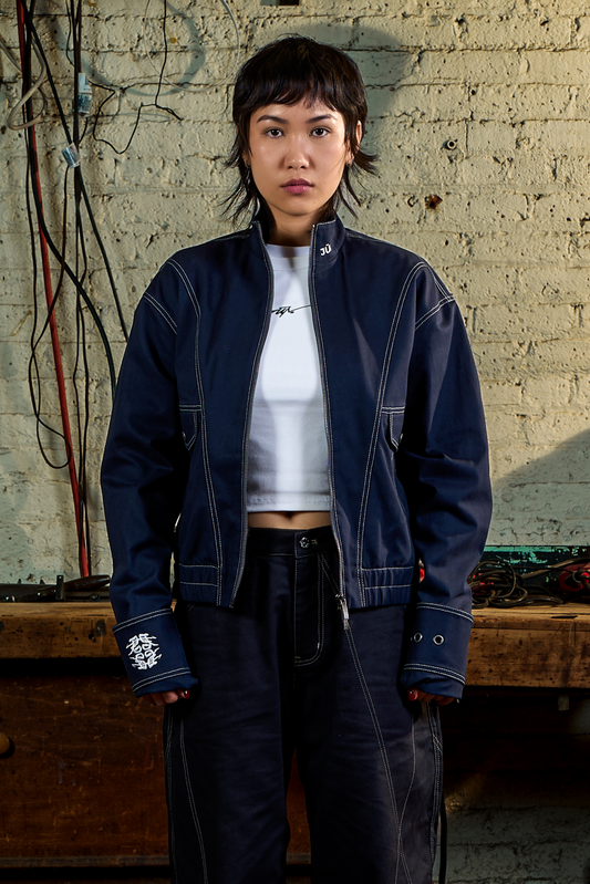 ONYX. JKT in navy — front, worn open, styled with a white crop top, garage setting